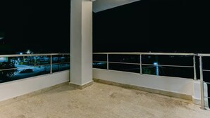 A balcony with a metal railing, a white pillar, and a view of a parking lot at night. - Penthouse con dos camas grande A-301 (Punta Cana)
