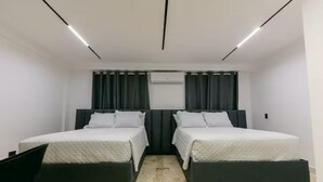 Moderni hotellihuone, jossa on kaksi sänkyä, taulutelevisio ja sisäänrakennettu ilmastointilaite.