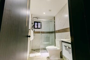 Une salle de bain moderne avec une douche à parois de verre, des toilettes blanches et un meuble-lavabo avec un miroir.