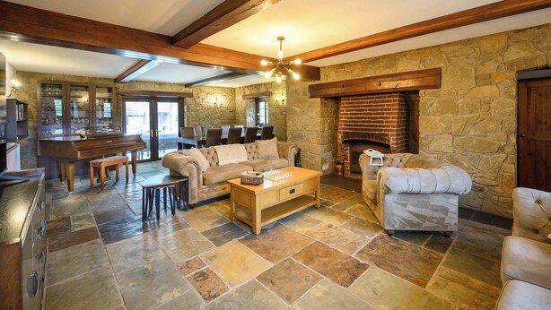 A spacious living room with a stone fireplace, a wooden coffee table, and a stone-tiled floor. - Exceptional Luxury at Laurel House by STAE-Homes (Magor)