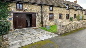 A stone building with a tiled roof, a wooden door, and a small garden area. - Exceptional Luxury at Laurel House by STAE-Homes (Magor)
