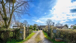 A rural road leading to a gated property with a stone wall and a sign reading "Laurel House." - Exceptional Luxury at Laurel House by STAE-Homes (Magor)