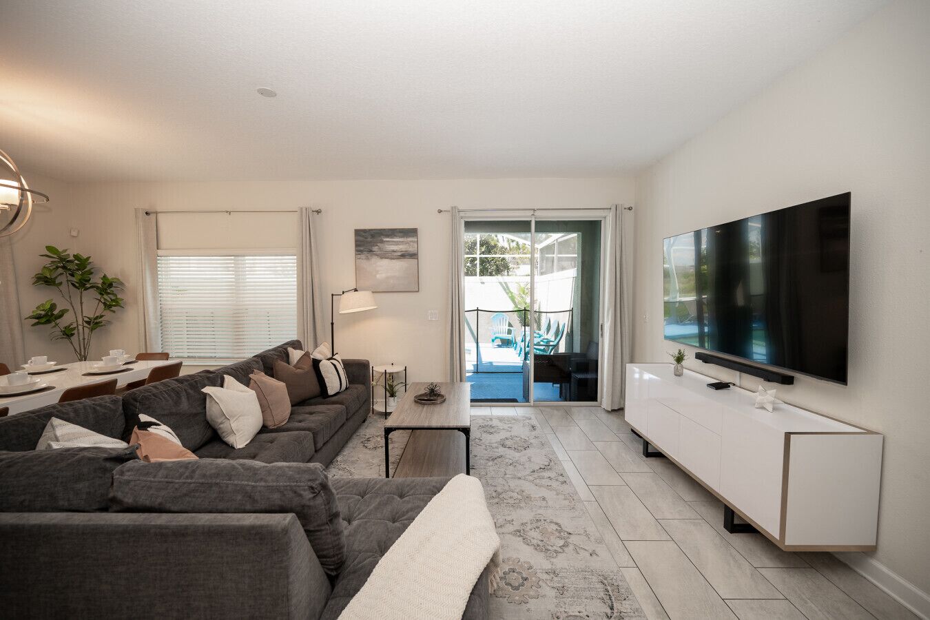 Una sala de estar moderna con un sofá gris, una televisión y un comedor.