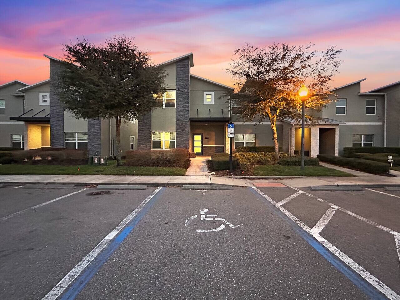A parking lot with a handicapped parking space, a building entrance, and a street lamp.