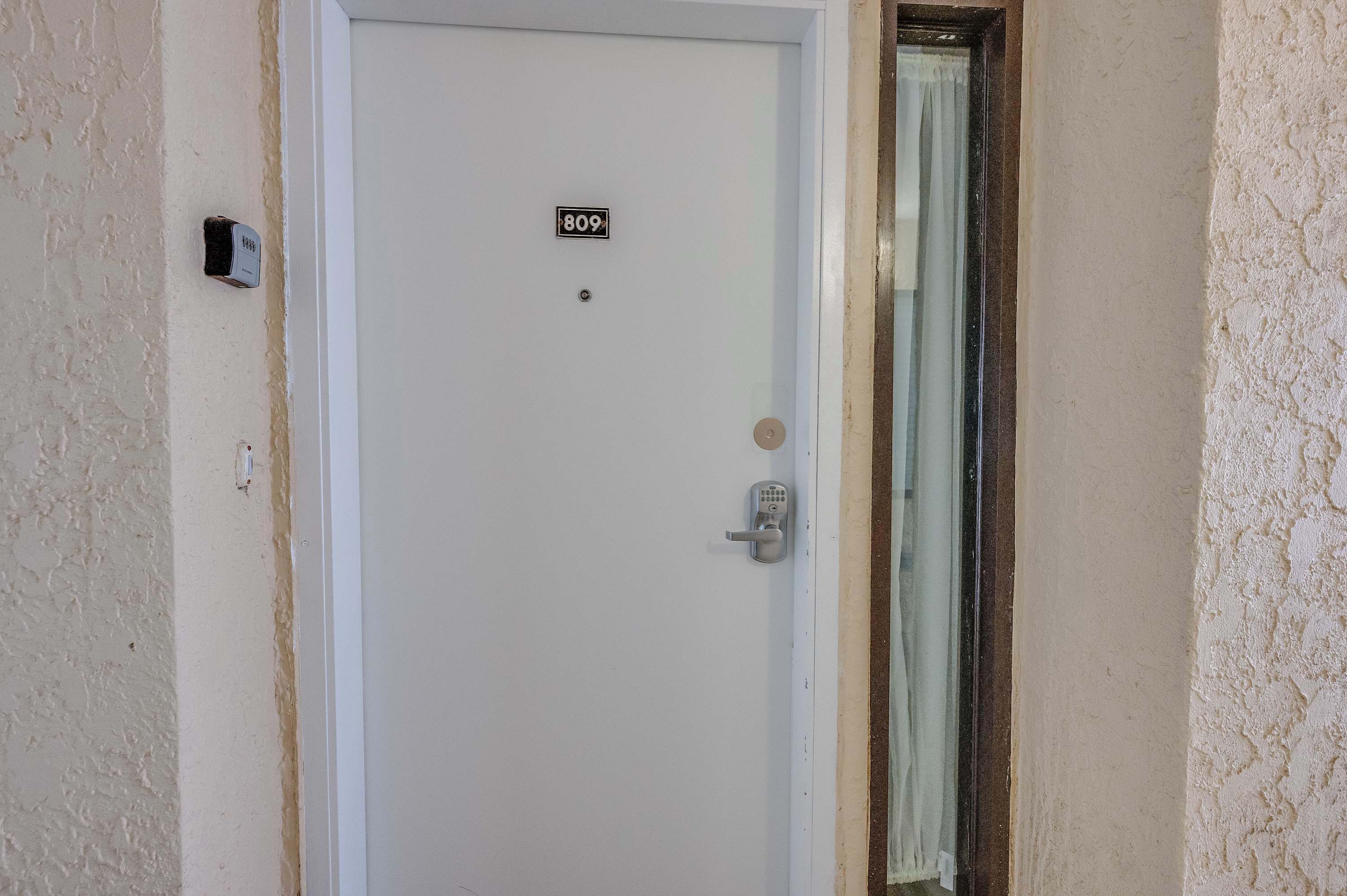 A white door with a number plate '809' and a keypad lock.