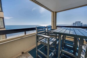 Een balkon met uitzicht op de oceaan en een gebouw in de verte.