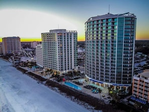 A high-rise hotel with multiple floors, a swimming pool, and a landscaped area with palm trees. - New Direct Ocean and City Views, Corner Suite,Nice (Myrtle Beach)