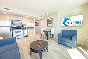 Eine moderne Küche mit Edelstahlgeräten, ein Essbereich mit Tisch und Stühlen sowie ein Wohnbereich mit Sofa und Couchtisch.