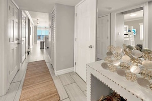 A hallway with white doors, a rug, and a decorative table with glass objects. - Luxury 2 Story Oceanfront Penthouse at the  Palms (Myrtle Beach)