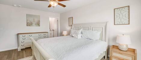 Un dormitorio con cama, mesita de noche, ventilador de techo y una puerta.