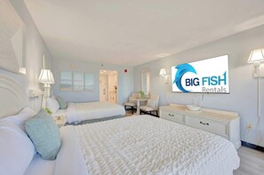 A hotel room with a large bed, a desk, and a chair. There is a television on the wall and a sign that reads 'BIG FISH Rentals.' - New Direct Oceanfront Studio, 6th Floor, Sandcastle South! (Myrtle Beach)