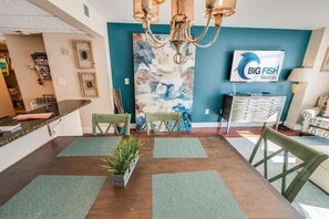 Un espace d’accueil avec un mur bleu, un lustre, des œuvres d’art encadrées, un bureau et une chaise.