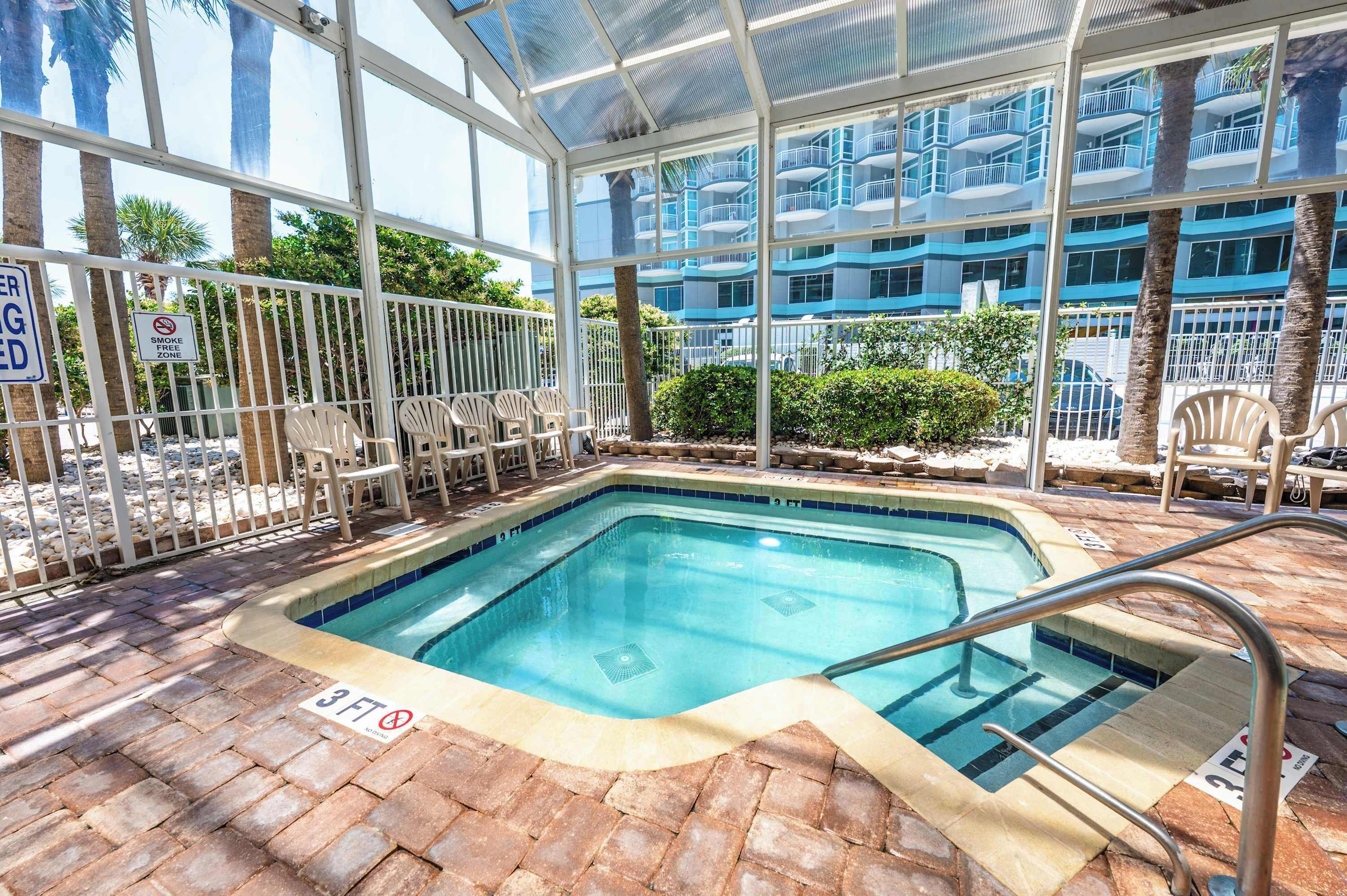 A pool area with a glass enclosure, a sign indicating a 3ft depth limit, and a no-smoking zone sign.