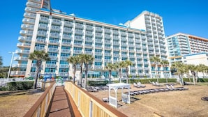 A large hotel with multiple balconies and a pool area with sun loungers.