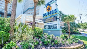 A Dunes Village Resort sign with a fitness center, a vacant room, and a Captain's Cafe & Bar.