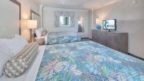 A hotel room with two beds, a TV, a desk, and a window with curtains. - Amazing Penthouse at Coral Beach with Heated Pools (Myrtle Beach)