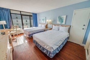 A hotel room with two beds, a desk, a chair, and a large window with curtains. - High Floor Studio, Oceanfront, Heated Pools,Views (Myrtle Beach)
