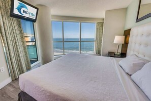 A hotel room with a large bed, a TV mounted on the wall, and a view of the ocean. - New Corner 6th FLOOR, Floor to Ceiling Glass Views (Myrtle Beach)