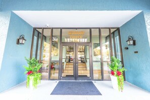 A hotel entrance with a glass door, a sign reading "SEAMARK TOWER," and two potted plants on either side. - Recently Renovated, Oceanfront, Amazing Views (Myrtle Beach)