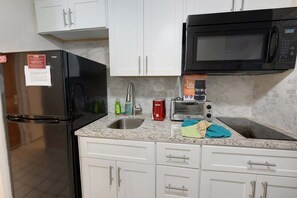 Eine Küche mit Kühlschrank, Mikrowelle, Toaster, Spüle und Schränken.