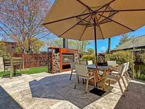 Une terrasse extérieure avec une table, des chaises et un grand parasol.