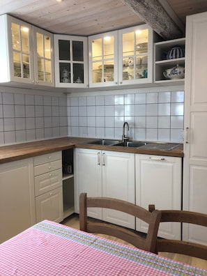 A kitchen with white cabinets, a wooden countertop, and a sink. - Peaceful country home with beautiful water view (Rudkøbing)