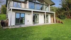 A modern two-story house with large glass windows, a balcony, and a well-maintained lawn. - Green Shutters (Pembroke)