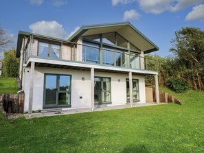 A modern two-story house with large glass windows, a balcony, and a well-maintained lawn. - Green Shutters (Pembroke)