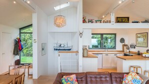 A modern kitchen with a 'Patrol' sign, a hanging light fixture, and a ship decoration on the wall. - Green Shutters (Pembroke)