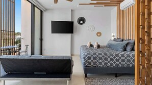 Un dormitorio moderno con cama, sofá, ventilador de techo, televisor y ventana.