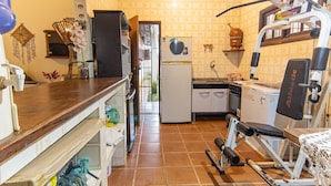 A compact kitchen with a refrigerator, oven, and a small dining area. - Casa com Piscina e rea Gourmet em Boi Ucanga (São Sebastião)