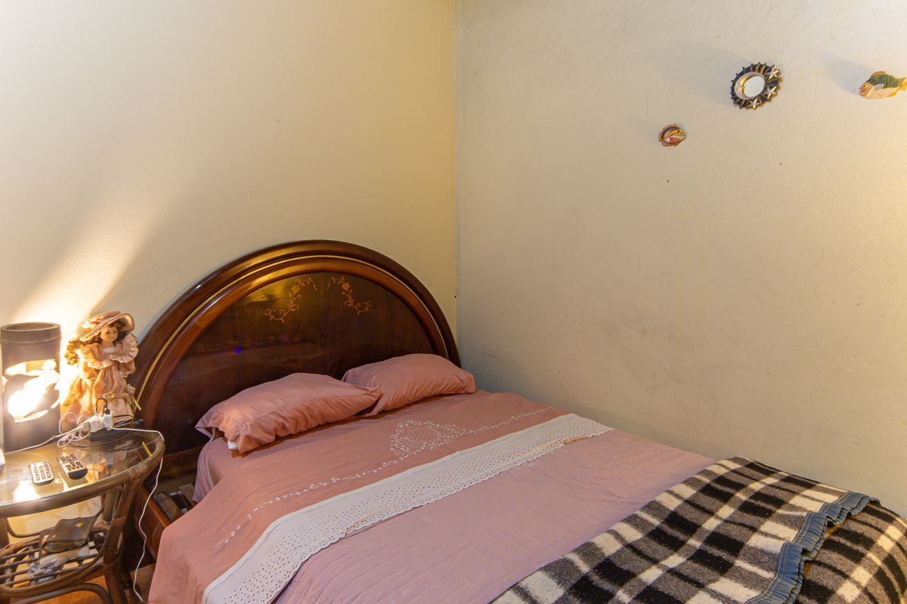 A bedroom with a wooden bed, a bedside table with a lamp, and a small table with a figurine.