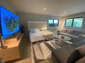 A modern bedroom with two beds, a TV, a sofa, and a coffee table. - Family Home w/ Kayaks, Hot Tub, Beach Access & Pickleball (Eastsound)