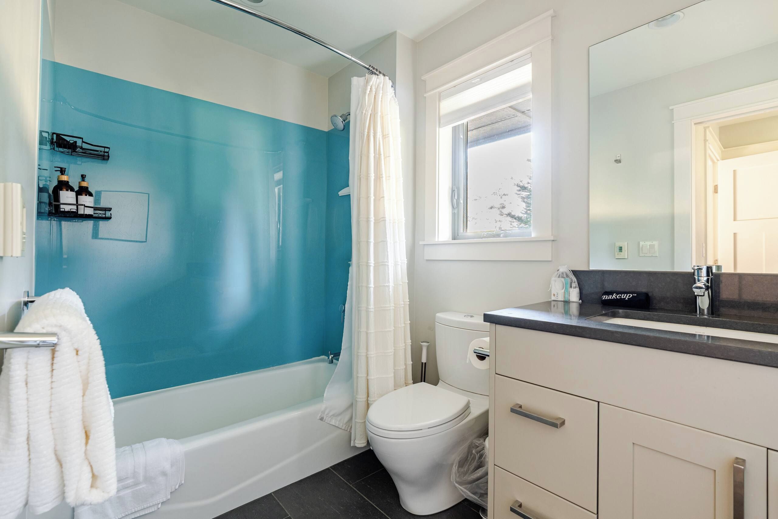 Un bagno con una vasca, un water e una finestra.