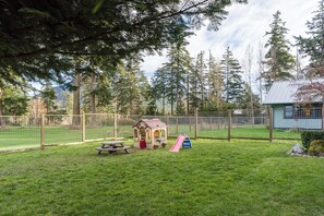A fenced backyard with a picnic table, a small playhouse, and a slide. - Family Home w/ Kayaks, Hot Tub, Beach Access & Pickleball (Eastsound)