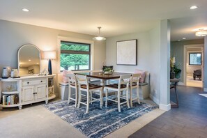 A dining area with a table and chairs, a white console with books, a mirror, and a window with a view of trees. - Family Home w/ Kayaks, Hot Tub, Beach Access & Pickleball (Eastsound)