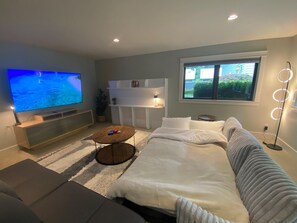 Un salon moderne doté d’un téléviseur à écran plat, d’un canapé, d’une table basse et d’une fenêtre offrant une vue agréable.