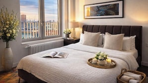 A modern hotel room with a large bed, a view of the city, and a framed artwork on the wall. - Canary wharf iconic London skyline view (London)