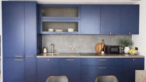 A modern kitchen with blue cabinets, a granite countertop, a microwave, and a dining area with a table and chairs. - Canary wharf iconic London skyline view (London)