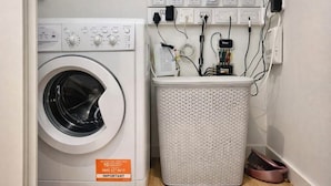A front-loading washing machine with a control panel and a white laundry basket. - Canary wharf iconic London skyline view (London)