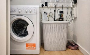 A front-loading washing machine with a control panel and a white laundry basket. - Canary wharf iconic London skyline view (London)