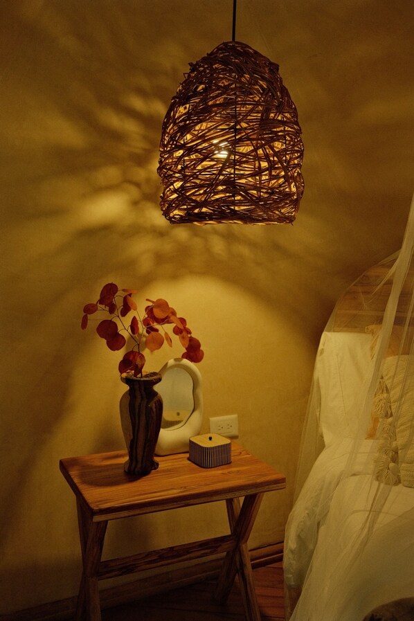 A bedside table with a vase of red leaves, a white lamp, and a small box.