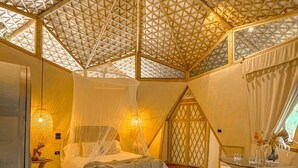 Ein Zimmer mit einem Bett, einem weißen Rundteppich, einem Holzstuhl und einem Tisch mit einer Vase.