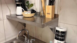 Uma cozinha com cafeteira, utensílios e toalhas de papel nas prateleiras.