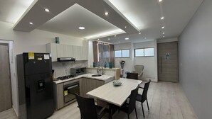 Eine moderne Küche mit Einbauherd, Spüle und Kühlschrank. Es gibt einen Essbereich mit Tisch und Stühlen.