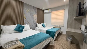 Ein Hotelzimmer mit zwei Betten, einer Marmorwand, einem Fenster mit Jalousien, einer Klimaanlage und einem Fernseher.