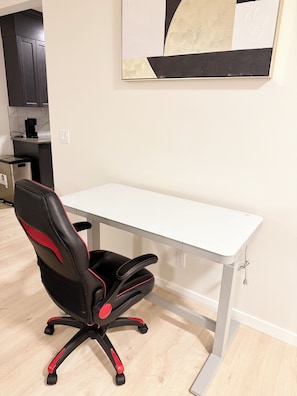 Una silla de oficina moderna con respaldo alto y reposabrazos, ubicada junto a un escritorio blanco.