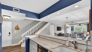 A modern kitchen with granite countertops, stainless steel appliances, and a white staircase.