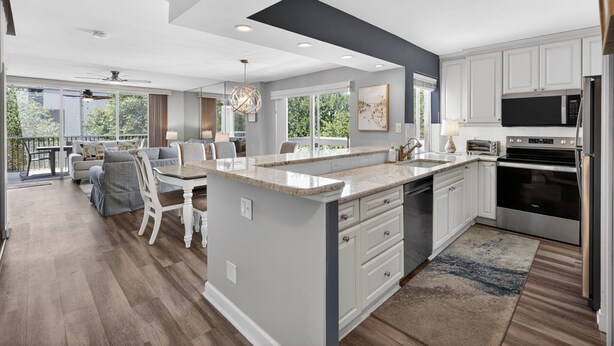A modern kitchen with white cabinets, a large island, and a view to the outdoors.