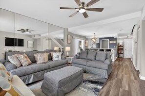 A modern living room with a sectional sofa, ottoman, and a large mirror.